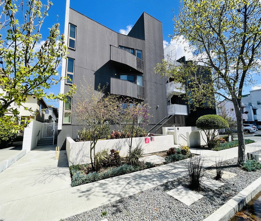 A modern building with a grey facade and a landscaped garden in front.