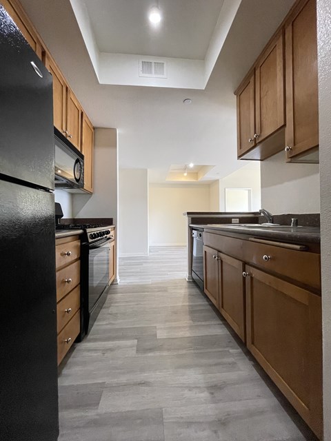A modern kitchen with wooden cabinets and black appliances.