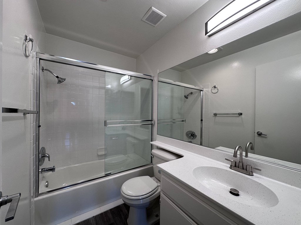 A white bathroom with a toilet, sink, and shower.