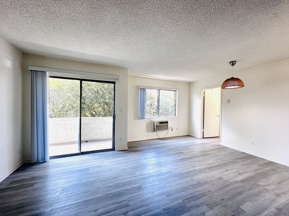 A spacious room with a sliding glass door and a wooden floor.