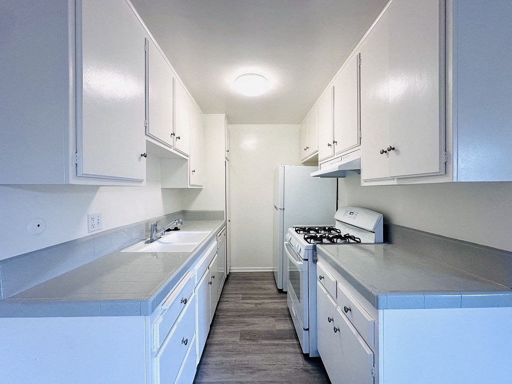 A kitchen with white cabinets and a stove top oven.