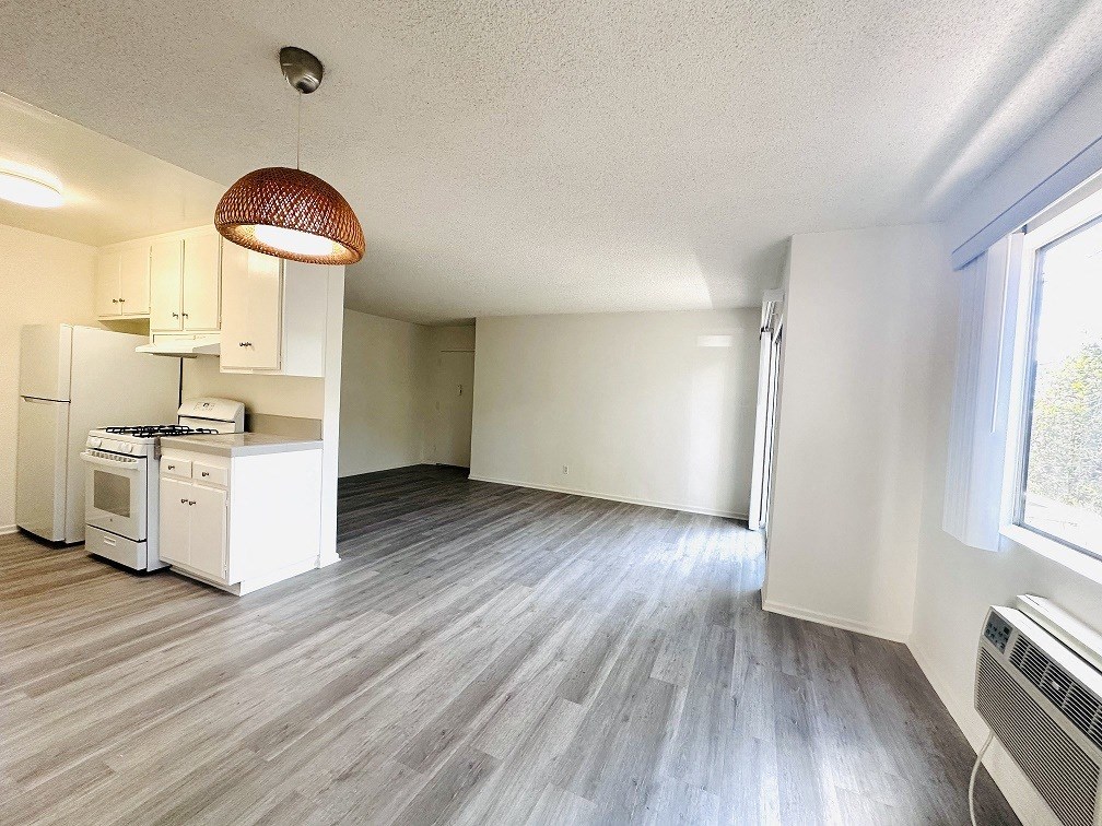 A kitchen with white appliances and a grey floor.