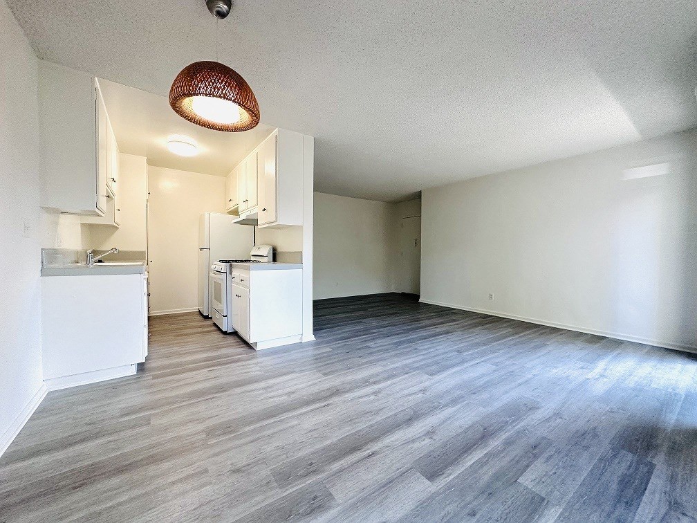A kitchen with white cabinets and a wooden pendant light.