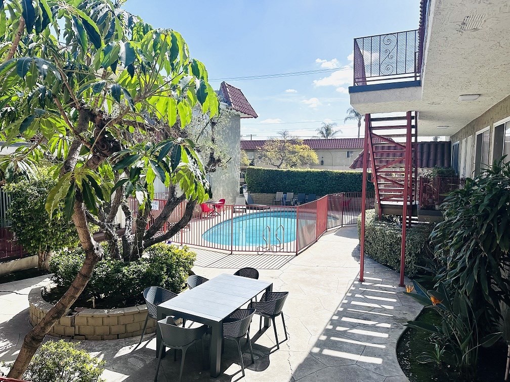 A patio with a table and chairs overlooking a pool.