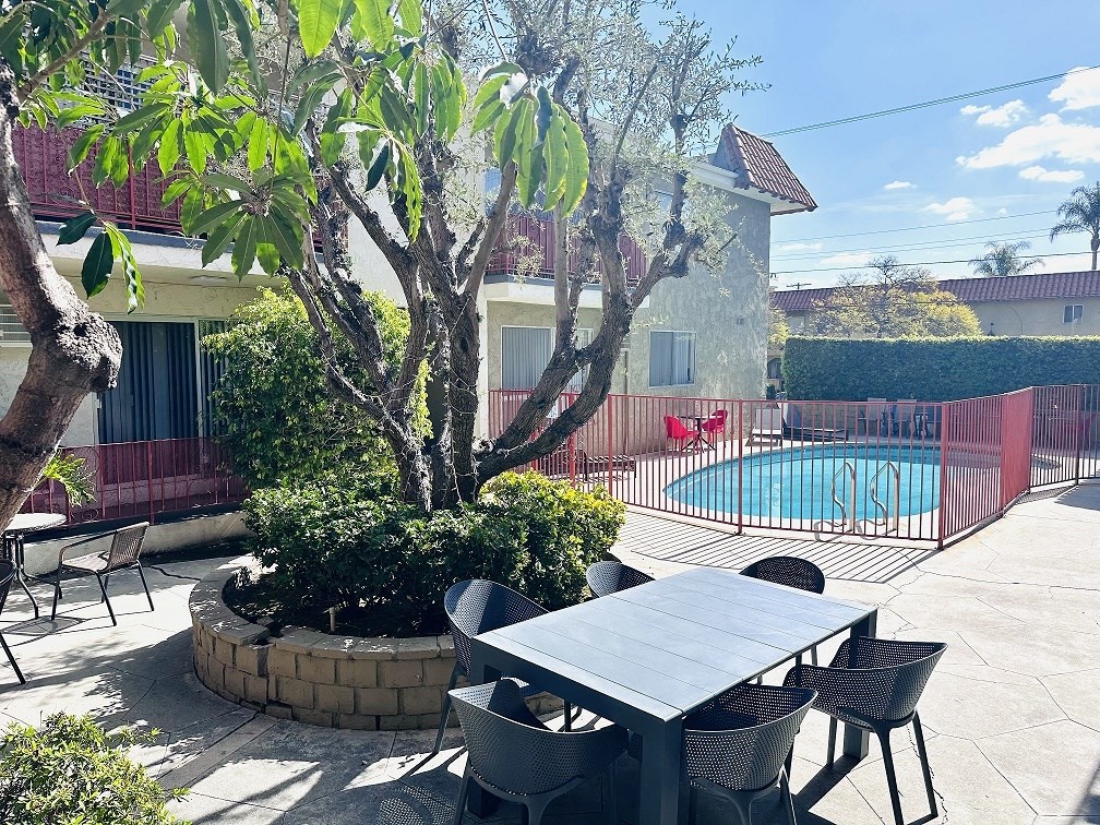 A backyard with a table and chairs and a pool.