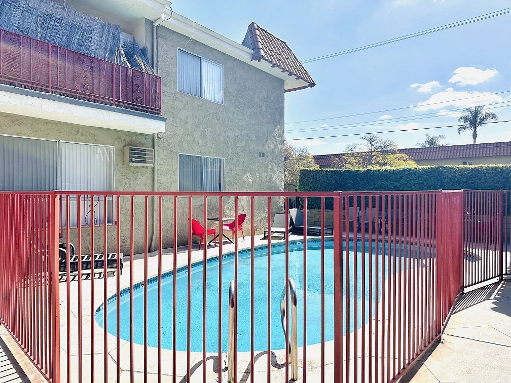 A red fence surrounds a small pool.
