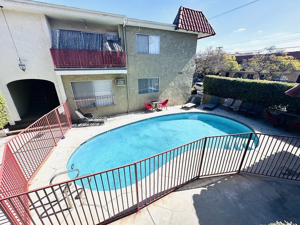 A small pool in a fenced in area outside a building.