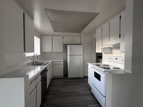 A white kitchen with a refrigerator, oven, and sink.