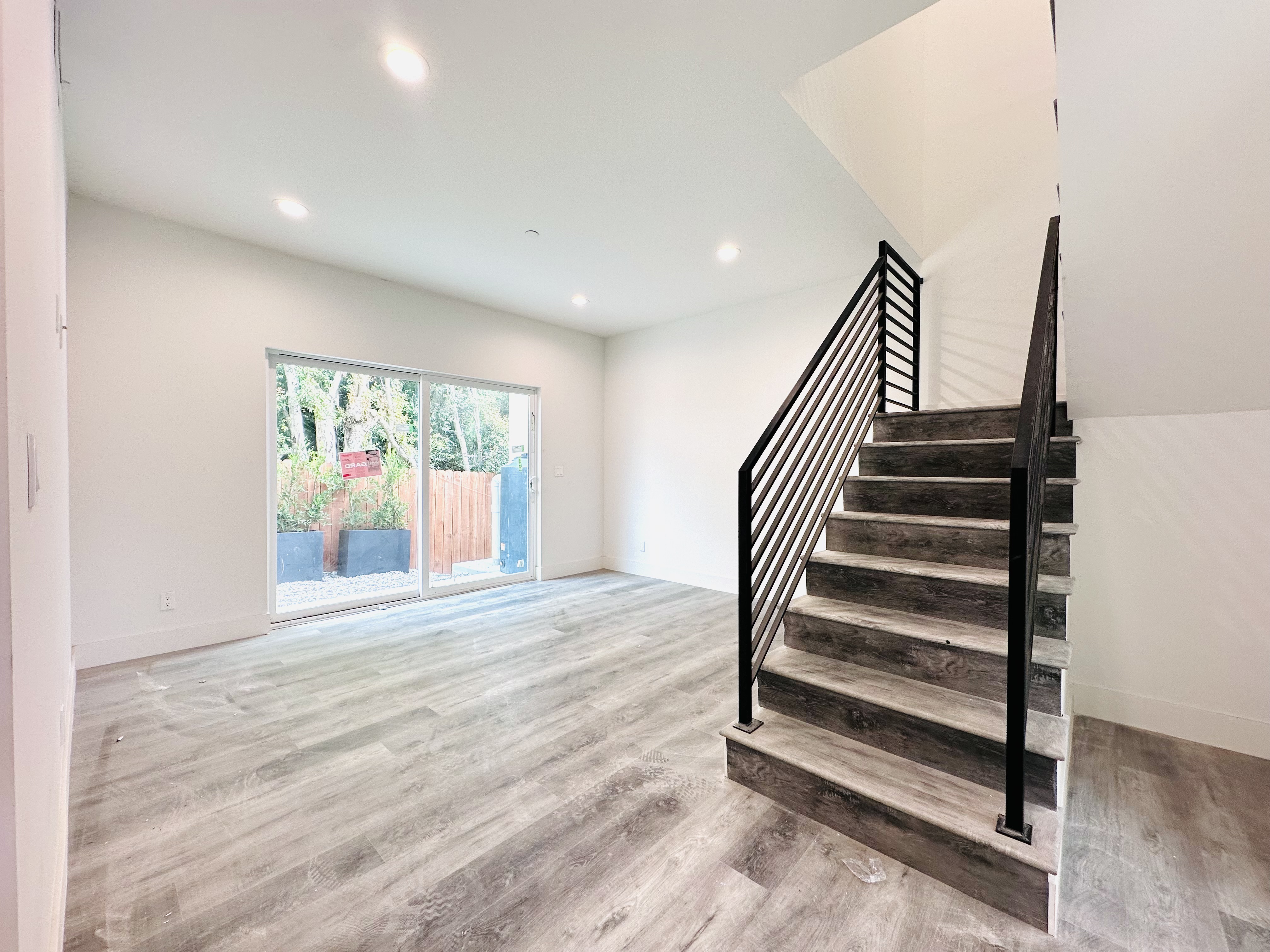 A wooden staircase with metal railings leads up to a bright room with a window.