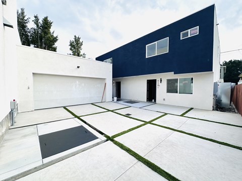 A modern house with a white and blue exterior and a black and white tiled driveway.