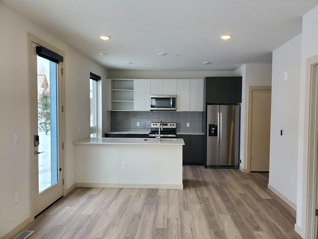 an empty kitchen and living room with a refrigerator and a sink