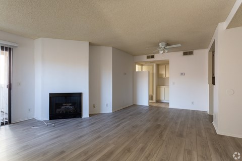 A living room with a fireplace and a fan on the ceiling.