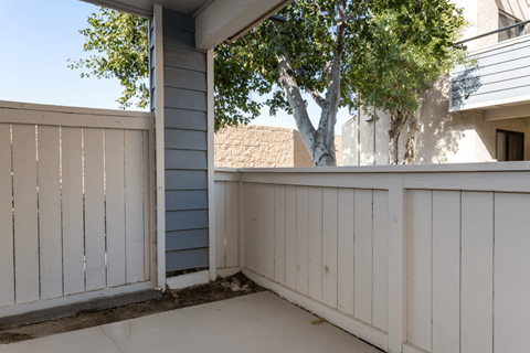 A white wooden deck with a tree in the background at Lido Apartments - 101-197 N Ridgeway, Anaheim, CA