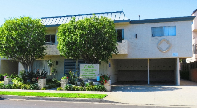 a white building with a sign and trees in front of it