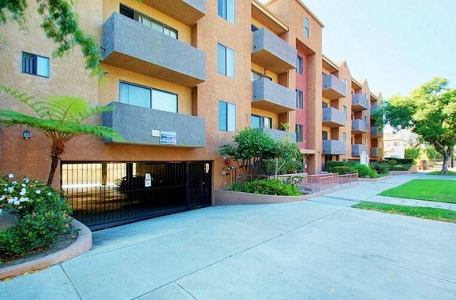 Apartment building with a black gate and a tree in front.