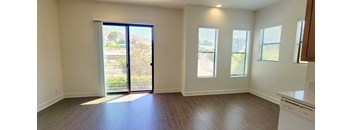 an empty living room with a door to a balcony