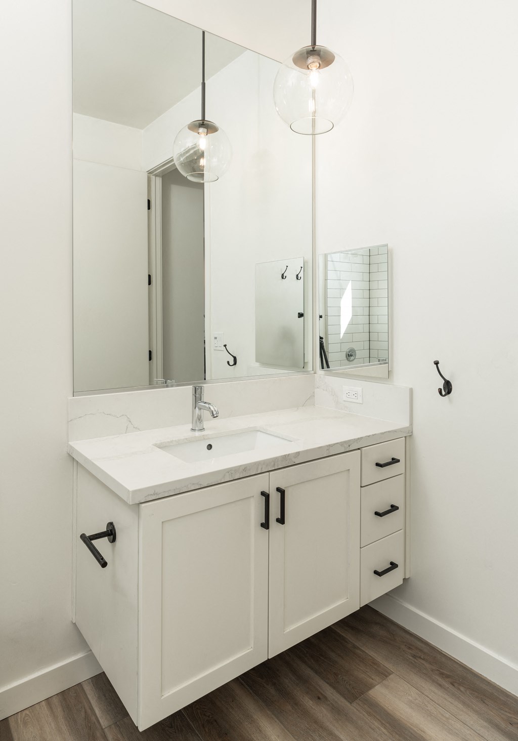 Bathroom floating vanity. White with brass hardware and hanging pendant light at Plaza Riviera, California