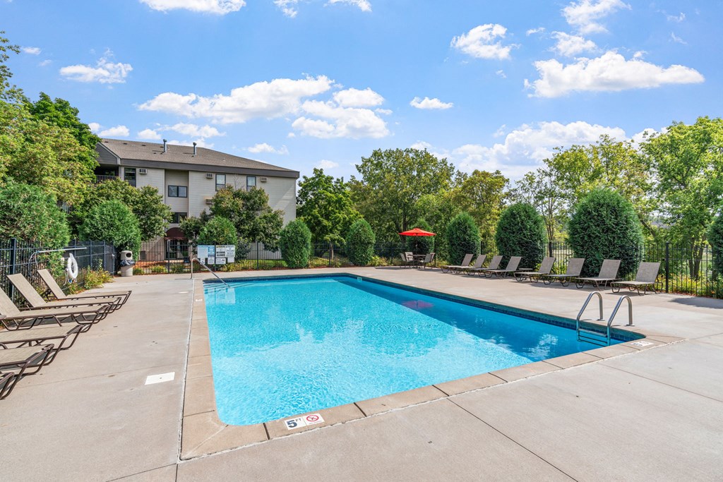 a swimming pool with chairs and a building in the background