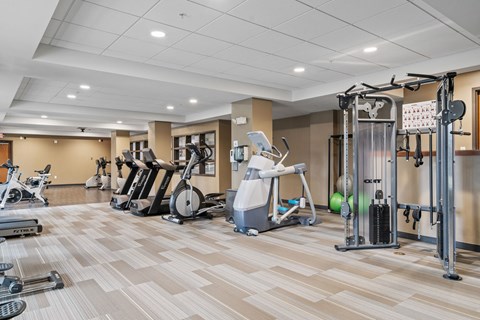 a gym with cardio machines and weights on a wooden floor