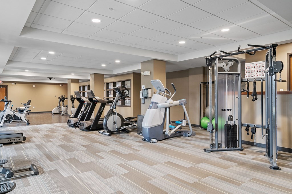 a gym with cardio machines and weights on a wooden floor