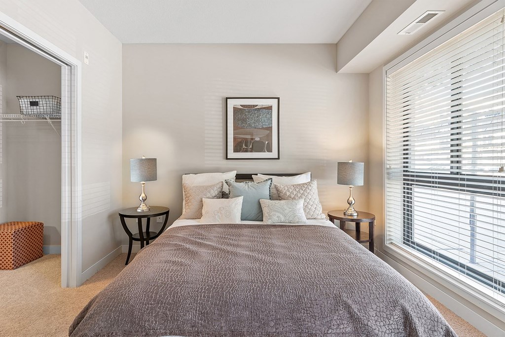 a bedroom with a large bed and two windows