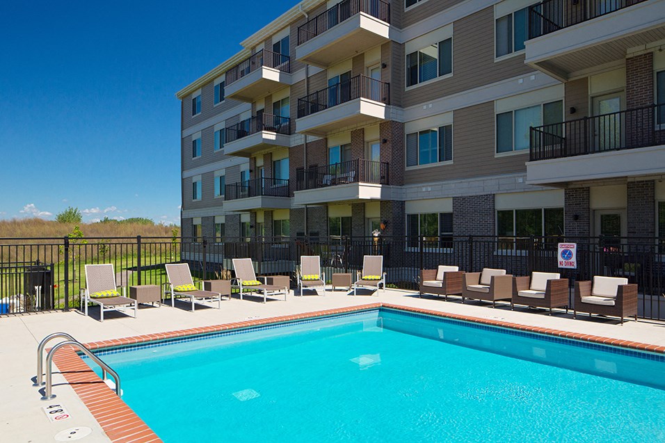 a swimming pool with lounge chairs next to a building