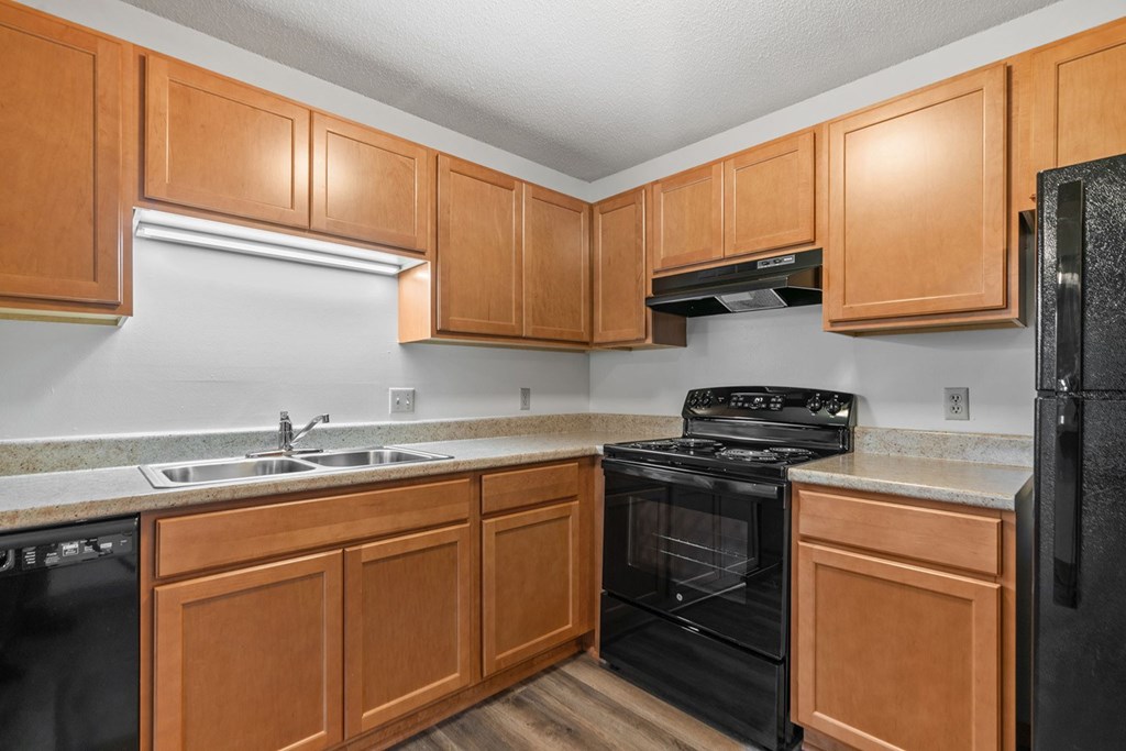 A kitchen with black appliances and wooden cabinets.