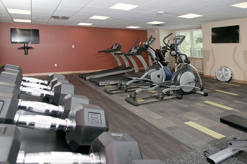 a gym with weights and a tv on the wall