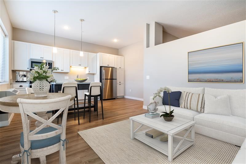 A modern living room with a dining area and kitchen in the background.