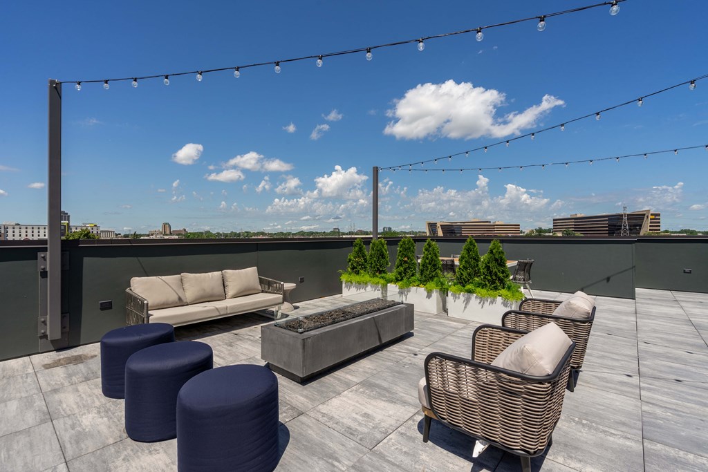 A rooftop patio with furniture and string lights.