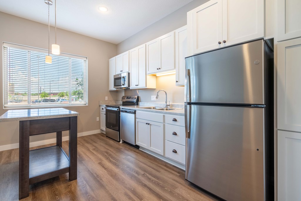A kitchen with a refrigerator, microwave, oven, and sink.
