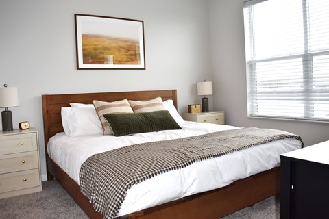 A bedroom with a bed, nightstand, and lamp.