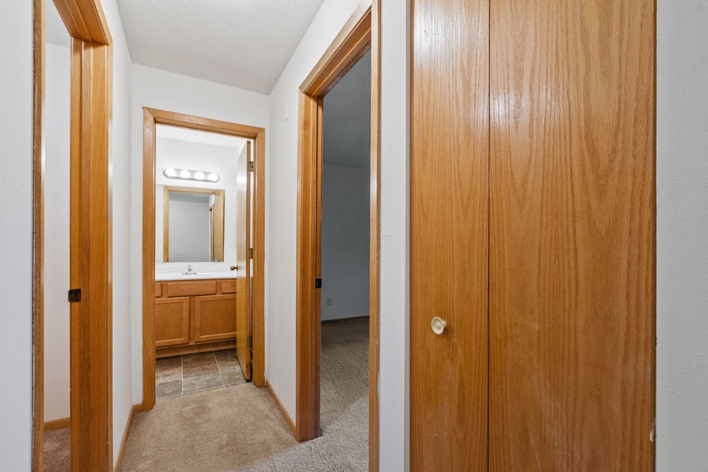 the entrance to a bathroom and a hallway with a door to a bedroom