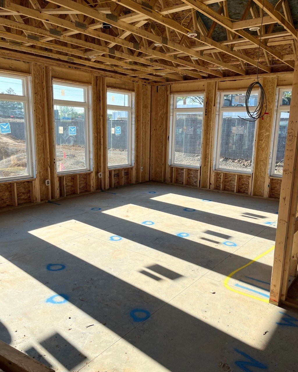 A room under construction with wooden beams and windows.