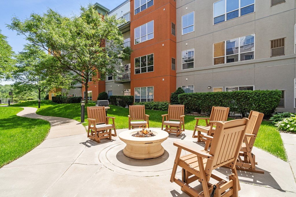 an outdoor patio with chairs and a fire pit in front of an apartment building