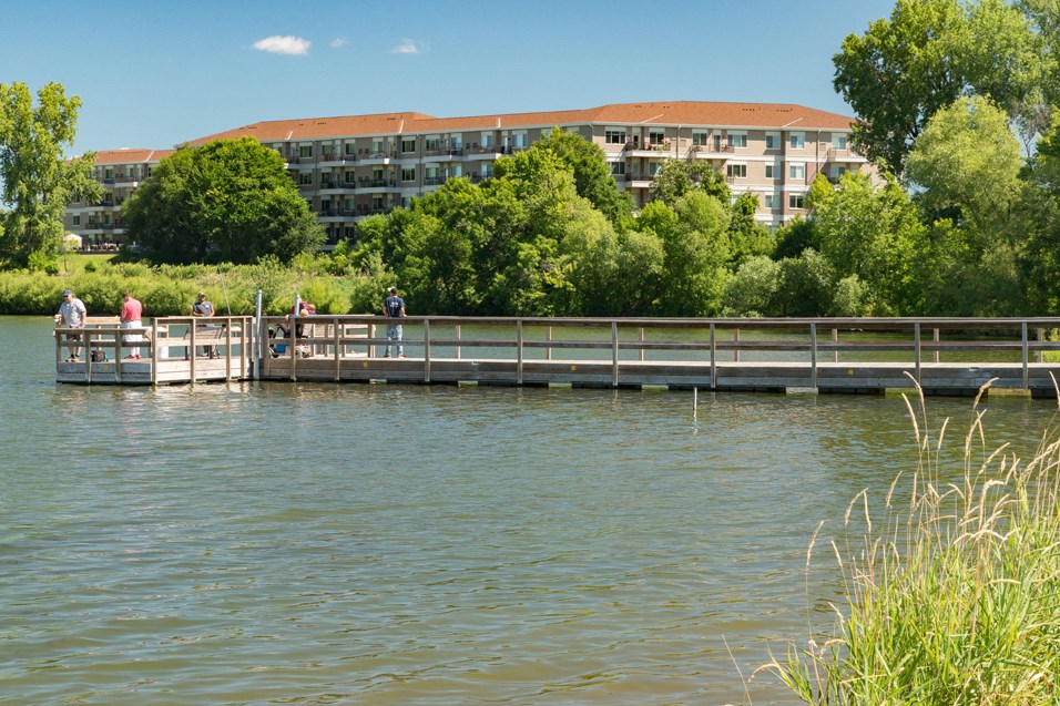 people standing on a dock on the water at a lake