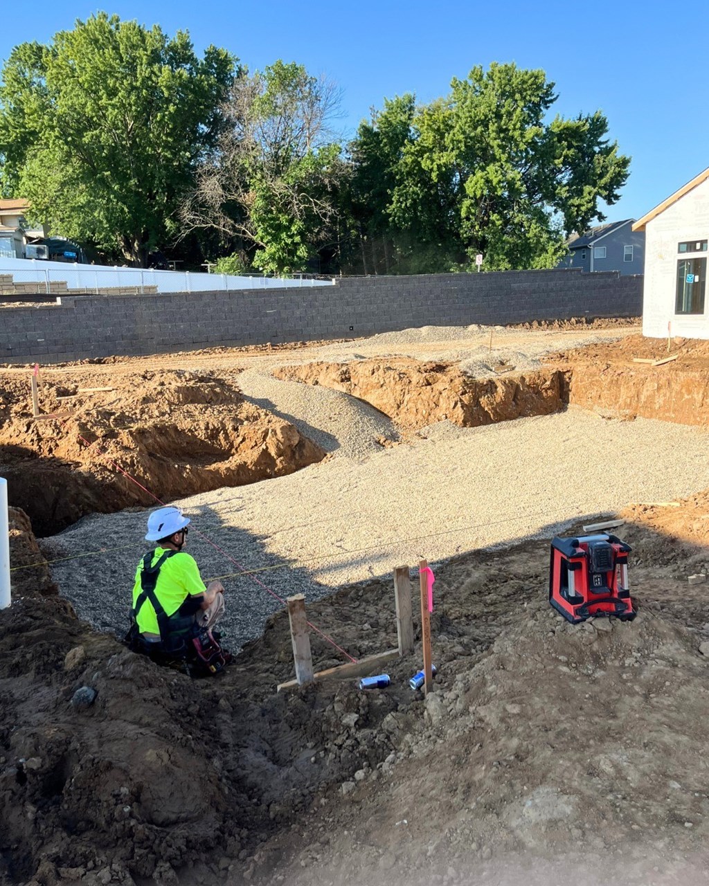 A construction worker is sitting on the ground with a toolbox beside him.