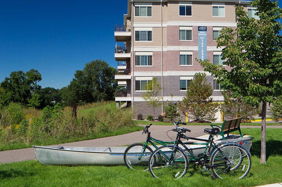 three bikes and a canoe in front of an apartment building