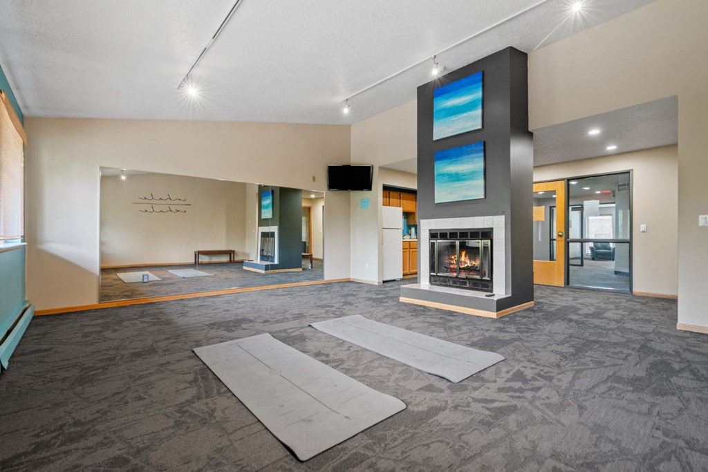 a large living room with a fireplace and yoga mats