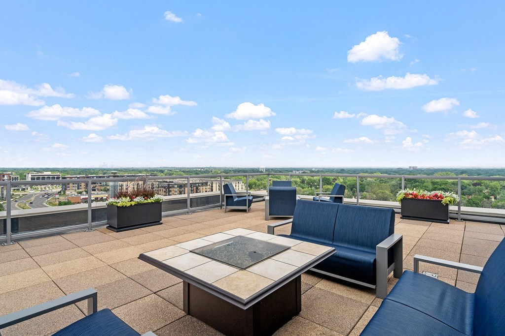 an outdoor patio with blue chairs and a firepit with a view of the city