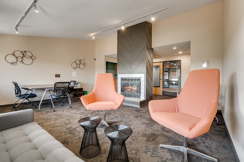 A living room with a fireplace and two orange chairs.
