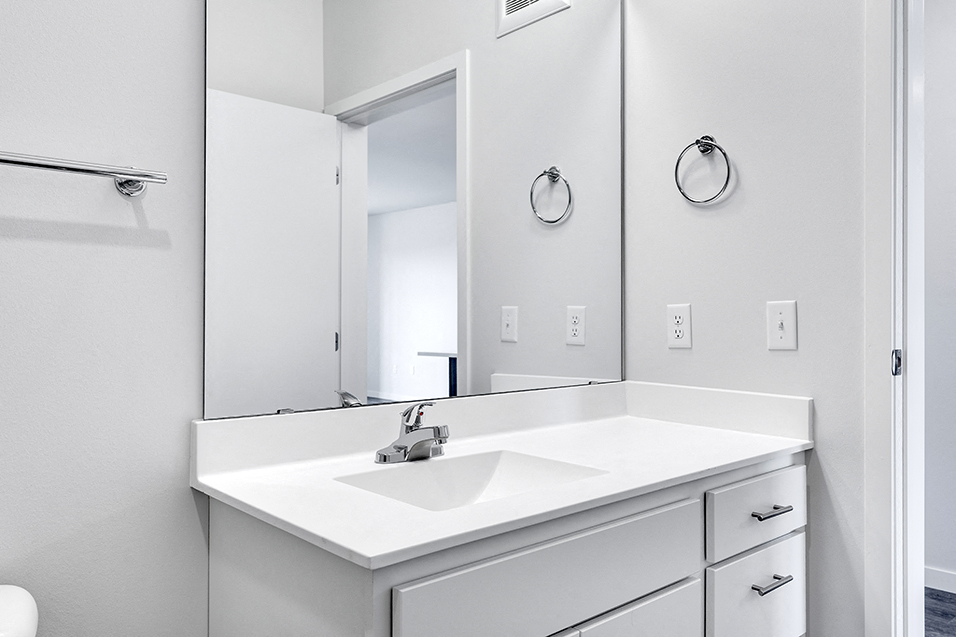 bathroom sink and mirror with white countertop, walls, and shelves