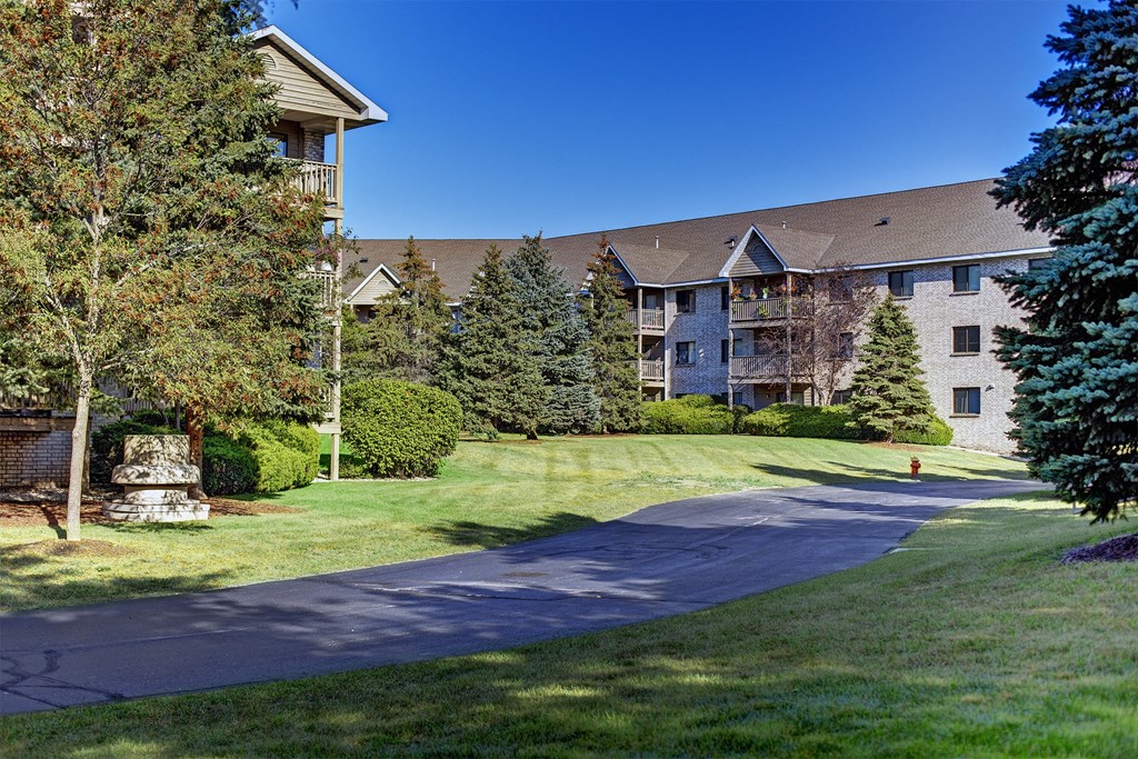 a pathway leading to an apartment building with trees and grass