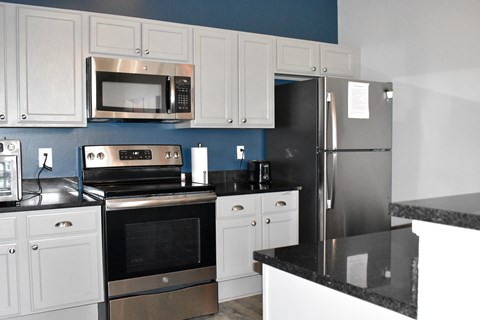 A kitchen with white cabinets and a black counter.