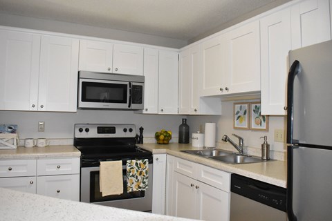 A kitchen with white cabinets and appliances.