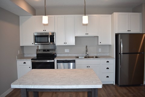 A kitchen with a table in the foreground and a refrigerator to the right.