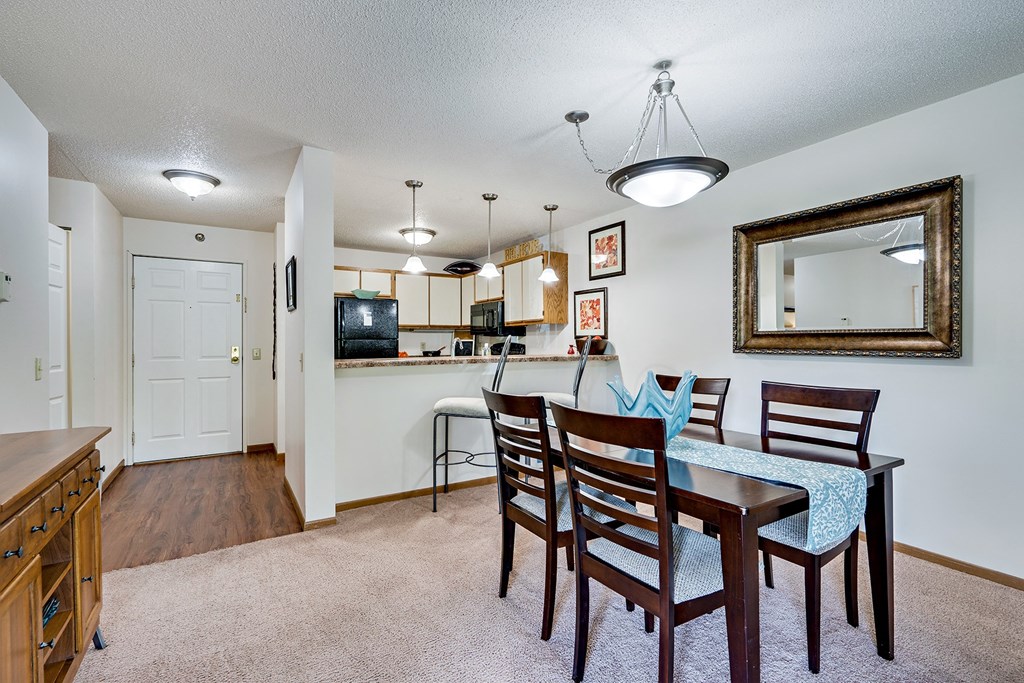 a dining area with a table and chairs and a kitchen in the background