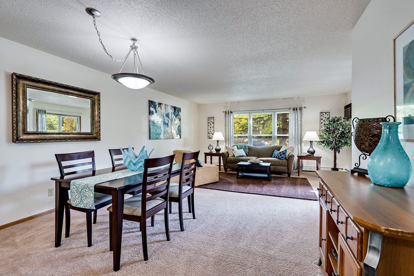 a living and dining room area with a table and chairs and a couch in the background
