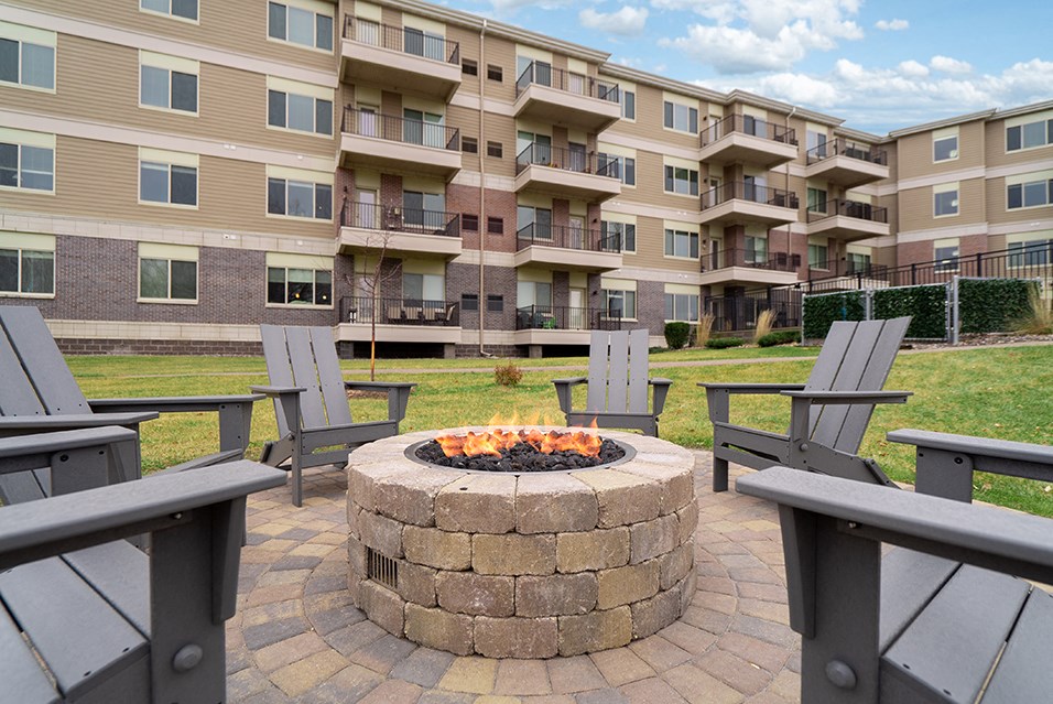 an outdoor patio with a fire pit in front of an apartment building