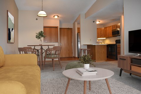 A living room with a yellow couch and a white coffee table.